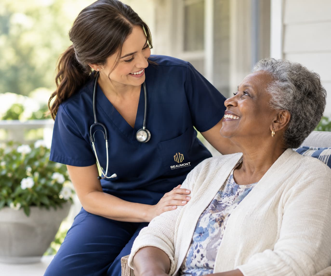 A nurse leaning in to talk with a resident in a sunlit lounge